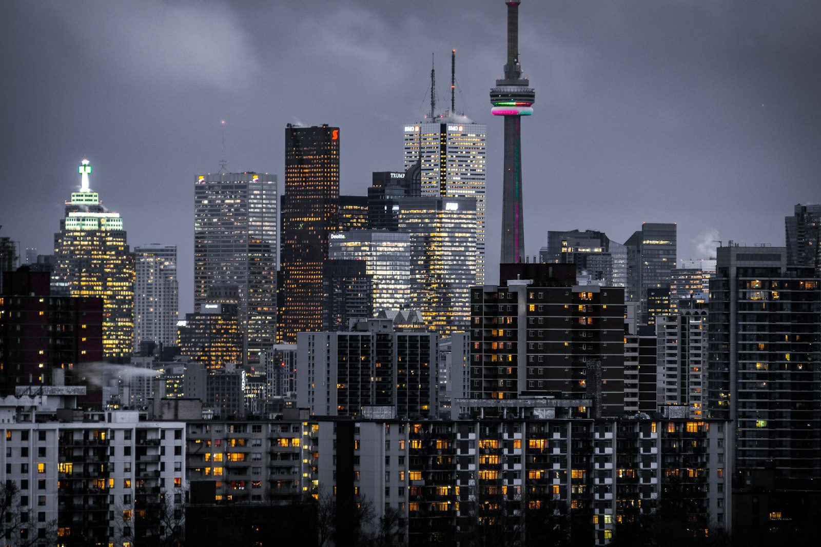A city skyline at dusk with illuminated towers and a broadcast tower